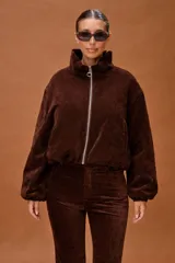 Campera bomber de pana con textura aterciopelada, cuello alto estructurado y cierre frontal con cremallera metálica. Posee mangas largas con puños elásticos y diseño corto.