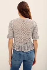 Sweater gris de tejido calado, con cuello redondo y mangas cortas abullonadas con puños elastizados.