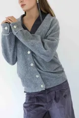 Cardigan de tejido suave en color gris, con escote en V, cierre frontal con botones y puños con detalle de botón.