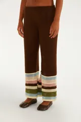 Pantalón de punto color marrón, de corte recto y tiro medio, con cintura elástica. Presenta diseño calado y franjas horizontales de colores en la parte inferior de las piernas.