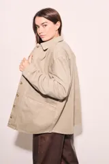 Sobrecamisa color beige de algodón peinado, corte recto, con cuello camisero, cierre frontal con botones y bolsillos de parche en el pecho.