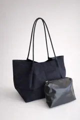 Bolso tipo shopper negro con acabado efecto gamuza, de diseño amplio y minimalista. Incluye un neceser pequeño a juego con cierre y doble asa de hombro.