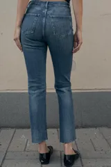 Jeans de tiro alto color marrón oscuro con acabado lavado, corte recto/flare y bajo cropped sin costuras. Presenta cinco bolsillos y cierre frontal con cremallera y botón metálico.