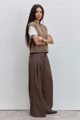 Chaleco de punto color marrón con cierre frontal de botones y detalle de costuras en contraste en los bordes. Presenta un diseño de cuello redondo y corte recto.