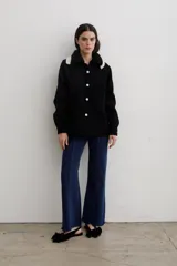 Camisa de paño de lana, color negro, con cuello tejido en contraste y cierre frontal de botones claros. Presenta bolsillos frontales y diseño de corte recto.
