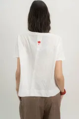 Remera blanca de algodón orgánico, con escote en V, mangas cortas y corte A-line. Cinta aplicada en la espalda con bordado de palmera.