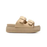 Sandalias plataforma tipo mule color taupe, con dos tiras anchas adornadas con hebillas cuadradas y remaches plateados decorativos. Cuenta con suela de plataforma alta con textura acanalada.