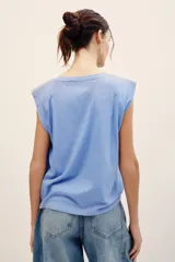 Musculosa celeste con hombreras estructuradas, cuello redondo y estampa frontal con la inscripción "LADY LUCK" y el número "28" en color azul oscuro.