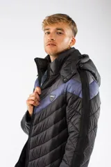 Campera puffer de nylon con relleno de guata, diseño capitoneado y capucha desmontable. Presenta un patrón de chevron en color azul sobre base negra, cierre frontal y bolsillos laterales con cierre.