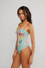 Body ajustado de nylon con estampado floral y paneles combinados de encaje y tul con lunares, tiras finas rojas y cierre frontal con cremallera.