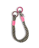 Accesorio decorativo para bolso tipo lazo, confeccionado en cuerda trenzada con patrón geométrico en tonos oscuros y claros, con detalles de hilo en color fucsia neón y argollas metálicas en los extremos.