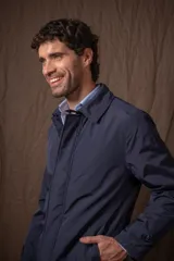 Trench azul marino de nylon, con cuello clásico, cierre frontal con botones y bolsillos laterales.