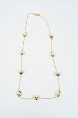 Collar largo de cadena fina plateada con dijes esféricos y orgánicos distribuidos a lo largo de la pieza.