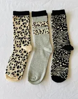 Pack de tres pares de medias de algodón con diseños estampados: un par color crema con estampado de leopardo negro, un par gris con banda superior con estampado de leopardo negro y un par blanco y negro con estampado de cebra y leopardo.