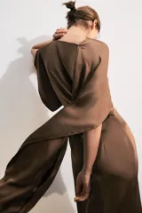 Vestido midi de satén color marrón, con cuello redondo, manga corta con capa fluida y cintura entallada con pliegues. Cuenta con falda recta con abertura en el bajo y cierre lateral con cremallera oculta.