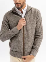 Campera tejida de punto jaspeado en tono azul, con cierre frontal completo, cuello alto y detalles de ribete en color marrón en los bolsillos y a lo largo del cierre. Presenta puños y ruedo acanalados.