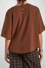 Blusa de manga corta color marrón, con escote redondo y diseño holgado.