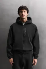 Sudadera con capucha de entrenamiento, confeccionada en tejido técnico de algodón con efecto neopreno. Presenta cierre frontal de cremallera, cuello subido, bolsillos laterales y un bolsillo en el pecho, todos con cierre de cremallera y acabado termofijado.