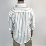 Camisa de manga larga blanca con rayas verticales grises y celestes, cuello italiano y corte semi entallado.