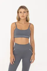 Top deportivo gris con breteles finos regulables y contorno inferior blanco.
