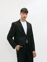 Ambo semi slim de color negro, compuesto por un saco estructurado de dos botones con solapa de muesca tradicional y un pantalón de corte contemporáneo.