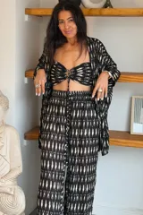 Conjunto de tres piezas de algodón con estampado abstracto en blanco y negro, compuesto por un kimono abierto de manga corta, un top estilo bandeau con nudo frontal y un pantalón largo de corte holgado.