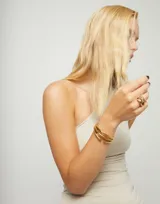 Pulsera rígida de aleación de metales bañada en oro de 18k, con diseño de tres tubos paralelos.