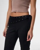 Pantalon negro de corte recto con cintura baja y detalle de solapa con tachas metálicas. Incluye un lazo lateral para ajuste y cierre.