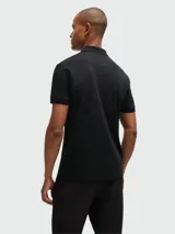 Polo de manga corta Boss confeccionada en algodón interlock, de color negro con estampado geométrico de líneas finas en tono dorado. Presenta cuello clásico con cierre de botones.