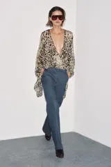 Pantalón de tiro alto confeccionado en algodón, con corte recto y diseño minimalista. Presenta bolsillos laterales, raya planchada en el delantero y cierre frontal con cremallera, botón y ganchos metálicos.