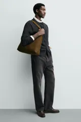 Bolso de hombro liso color verde militar, con compartimento principal con cierre de imán y un bolsillo interior con cremallera. Tiene un asa de hombro.