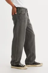 Jean de hombre color gris oscuro, de corte recto y holgado, con tiro bajo y cierre de bragueta. Cuenta con cinco bolsillos.