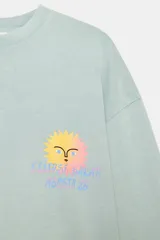 Camiseta de algodón con efecto lavado en color verde menta, de corte oversize, cuello redondo y manga larga. Presenta un pequeño estampado delantero diseñado por Agustina Shuan.