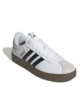 Championes Adidas VL Court 3.0 de estilo urbano, con capellada de cuero sintético blanco, icónicas tres tiras laterales en negro y puntera de gamuza en tono gris claro. Presenta una suela vulcanizada de color marrón oscuro y cierre mediante cordones.