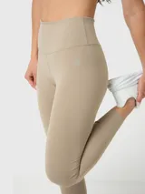 Conjunto deportivo de dos piezas compuesto por un top deportivo de escote redondo y calzas largas de tiro alto, ambos en color beige. El set destaca por su diseño minimalista y ajuste cómodo.