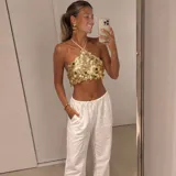 Top halter dorado con diseño de lentejuelas circulares colgantes y tiras finas ajustables al cuello y la espalda.