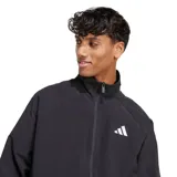 Campera deportiva Adidas de hombre, color negro, con cierre frontal y cuello alto. Presenta el logo Badge of Sport de Adidas en blanco en el lado izquierdo del pecho. Tiene puños y cintura elásticos.