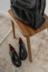 Botinetas negras con suela track, combinando cuero texturizado en la parte frontal y cuero charolado en la parte trasera. Diseño de caña baja con detalle de corte lateral.
