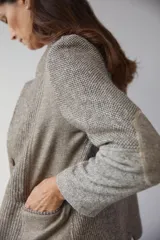 Chaqueta corta color marrón con cuello solapa y diseño con patchwork de telas. Manga larga con detalle de coderas aplicadas. Cierre frontal mediante botones y bolsillos ojal. Con forro.