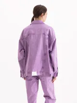Campera oversize de denim de puro algodón, con lavado efecto nevado en tono lila. Cuenta con mangas largas, bolsillos frontales con solapa y cierre de botones metálicos.