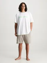 Conjunto de pijama Calvin Klein compuesto por una remera blanca con logo verde y un short beige con detalles en verde.