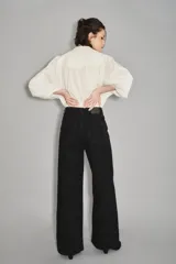 Jean de corte oxford en color negro, con tiro alto y diseño de pierna ancha. Confeccionado en denim de algodón, presenta cierre frontal con botón y bolsillos laterales y traseros.