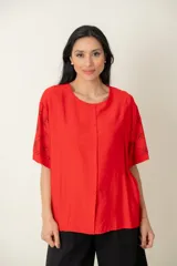 Blusa roja de viscosa con estampado de flores negras en las mangas, corte holgado, cuello redondo, cierre frontal con botones y tajos laterales.