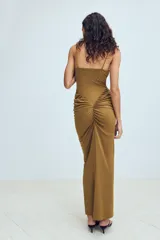 Vestido largo color tostado con diseño estilo corsé, escote corazón con aros y tirantes finos. Presenta un corte ajustado en la cintura con detalle de frunces laterales que aportan volumen a la falda.