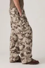 Pantalón cargo de corte holgado con estampado camuflado en tonos tierra. Presenta cintura elástica con cordón ajustable, bolsillos laterales tipo cargo y diseño de pierna ancha.