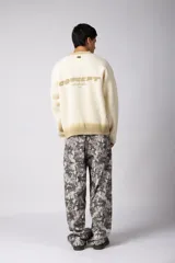Sweater de punto acanalado con diseño degradado de negro a gris en el cuello y el ruedo. Presenta un corte regular y un pequeño bordado central en el pecho.