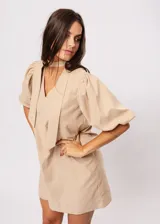 Vestido corto color beige, de corte oversize, con escote en V y mangas globo. Incluye cinturón marrón con hebilla dorada.