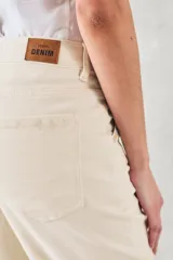 Pantalón jean color crudo, de tiro medio y corte recto, con bolsillos delanteros con bordado de motivos geométricos en tonos celeste y naranja.