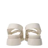 Sandalias chunky de color marfil con plataforma y suela dentada. Presentan dos tiras frontales anchas con cierre de velcro decoradas con pequeños tachas doradas, y una tira trasera ajustable.