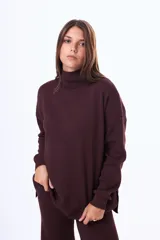 Buzo tejido de punto color negro, con cuello alto, manga larga y corte holgado con aberturas laterales en el ruedo.